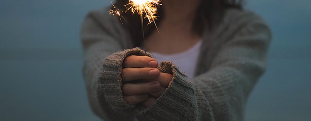 woman holding a lit sparkler in front of her