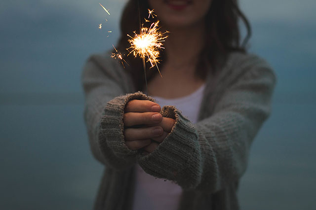 woman holding a lit sparkler in front of her